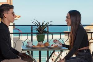 a man and a woman sitting at a table with food at La Piazzetta Sea Rooms in Balestrate