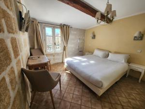 a bedroom with a bed and a table and a chair at Hôtel du Palais des Papes in Avignon