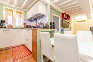 a kitchen with white cabinets and white chairs at Charming Mezzanino in Siena