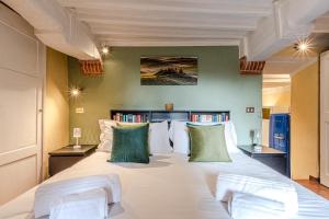 a bedroom with a large white bed with green pillows at Charming Mezzanino in Siena