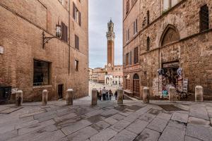a group of people walking down a street between buildings at Charming Mezzanino in Siena