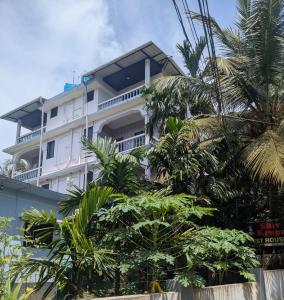 a white building with palm trees in front of it at shivkrupa Guest house in Arambol