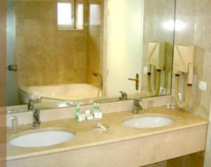 a bathroom with two sinks and a mirror at Hôtel des Pyrénées in Saint-Jean-Pied-de-Port
