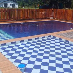 a swimming pool with a checkerboardkered floor in a backyard at Forest Gate Backpackers in Plettenberg Bay