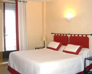 a bedroom with a bed with two red pillows at Hôtel des Pyrénées in Saint-Jean-Pied-de-Port