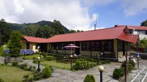 a resort building with a red roof and a patio at Hotel mardi station and restaurent in Astam