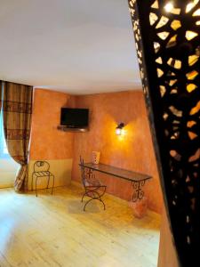 a room with a table and a tv on the wall at Hotel L'Astrolabe in Oloron-Sainte-Marie