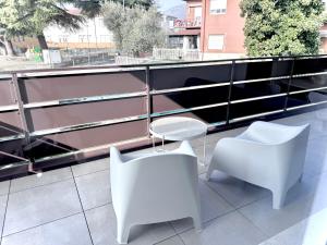 a balcony with white chairs and a table and chairs at Pantone - Sarnico Color Suites in Sarnico