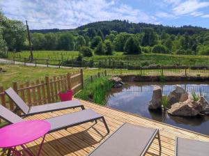 a deck with two chairs and a pond at Le Moulin de la Fortie, maison d'hôtes in Viscomtat