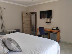 a bedroom with a bed and a desk with a computer at Petalite villa in Maun