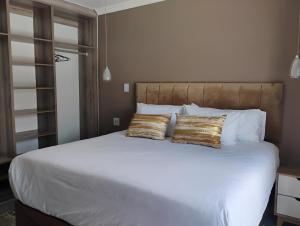 a bedroom with a large white bed with two gold pillows at Petalite villa in Maun +10 photos