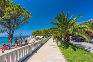 people walking along a sidewalk next to the beach at House Tinac in Crikvenica