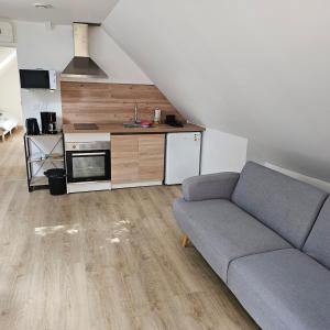 a living room with a couch and a kitchen at Hébergement Cosy in Bourg-et-Comin
