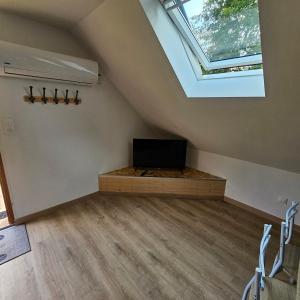 a attic room with a tv and a window at Hébergement Cosy in Bourg-et-Comin