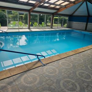 a swimming pool with blue water in a building at Hébergement Cosy in Bourg-et-Comin
