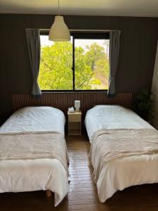 two beds in a room with a window at Matsudo in Matsudo