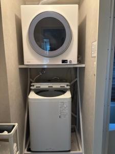 a microwave sitting on a shelf next to a washing machine at Matsudo in Matsudo
