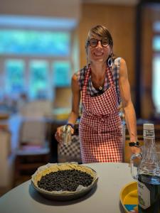 a woman in an apron standing next to a table with a pie at La Maison de Marie in Les Rouges-Eaux +45 photos