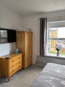 a bedroom with a bed and a dresser and a window at Crispin House in Hunstanton