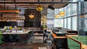 a restaurant with tables and chairs and windows at Hotel Rothschild 22 - FATTAL COLORS in Tel Aviv