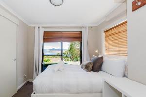 a bedroom with a white bed and a large window at 10 Kanangra Crescent - Entire in Jindabyne