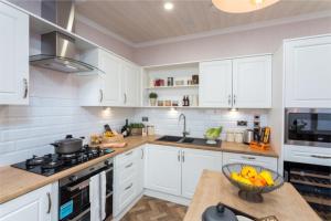 a kitchen with white cabinets and a bowl of fruit on a counter at Lyndale Lodge in Pulrossie +3 photos