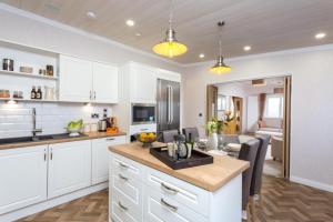 a kitchen with white cabinets and a dining room at Lyndale Lodge in Pulrossie