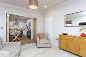 a living room with a couch and a chair and a kitchen at Lyndale Lodge in Pulrossie