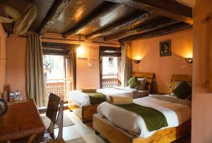 a bedroom with two beds and a table and a window at Bandipur Bazar Ghar in Bandipur