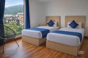 two beds in a room with a large window at The Blue Jay Hostel in Rishīkesh