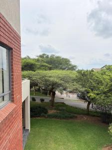 a window of a brick building with a yard with trees at The golf estate gateway in Roodepoort