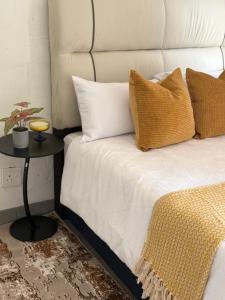 a bed with yellow and white pillows and a table at The golf estate gateway in Roodepoort +14 photos
