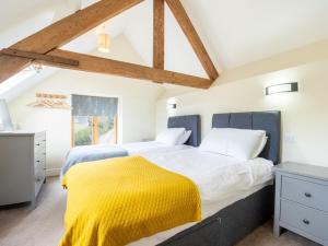 two beds in a bedroom with a yellow blanket at 2 Bed in Crediton oc-72791 in Coldridge