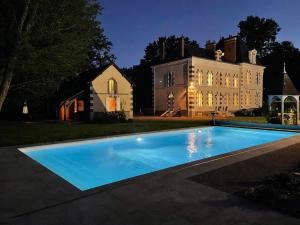 a large blue swimming pool in front of a house at La Chênaie - Suites individuelles dans un domaine d'art contemporain et nature in Gien