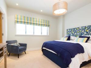 a bedroom with a bed and a chair and a window at 3 Bed in Bideford oc-52079 in Westward Ho