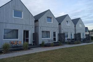 a row of gray houses with benches in a yard at PoProstuDomki in Niechorze