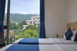 a bedroom with a bed and a large window at The Blue Jay Hostel in Rishīkesh