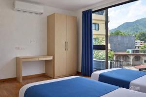 a bedroom with two beds and a large window at The Blue Jay Hostel in Rishīkesh