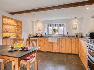 a kitchen with wooden cabinets and a table and chairs at 2 Bed in Tiverton oc-77442 in Washfield