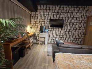 a living room with a couch and a tv on a wall at TOKYO-W-INN Asakusa in Tokyo
