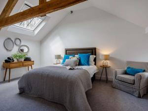 a bedroom with a bed with blue pillows and a chair at 4 Bed in Honiton oc-45563 in Payhembury