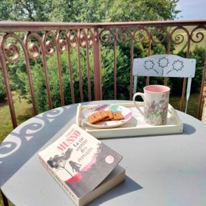 a table with a book and a cup and a plate of food at Chambres d'Hôtes Le Loubet in LʼIsle-Jourdain