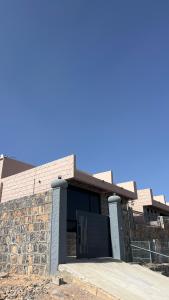 a building with a black door and a stone wall at نزل المنظر الليلي in Al Ḩamrāʼ