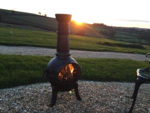 a black stove sitting on the ground with the sunset in the background at 2 Bed in Crediton oc-78468 in Cheriton Fitzpaine