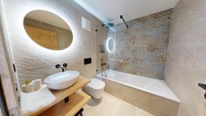 a bathroom with a sink and a tub and a toilet at Alphubel PEAK in Saas-Fee +94 photos