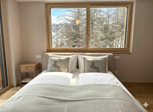a bedroom with a large bed with a window at Alphubel PEAK in Saas-Fee