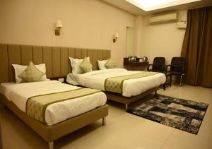 a hotel room with two beds and a table at TTAMAASHA INNN in Chinhat