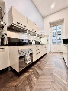 a kitchen with white cabinets and a wooden floor at Le Chouette Loft in Dijon