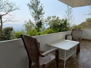 a table and chairs on a balcony with a view at kollanoor guest house in Madikeri