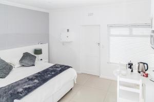 a white bedroom with a bed and a desk at Studio On Sea in Wilderness